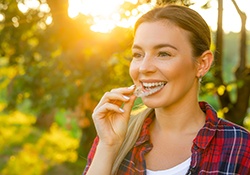 Woman smiling while inserting Invisalign aligner