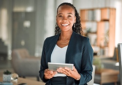 Woman smiling while holding tablet in office