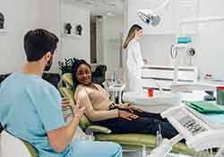 Emergency dentist talking to smiling patient in dental office