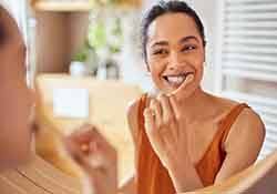 Woman smiling while brushing her teeth