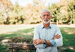 Senior man outside smiling with arms folded