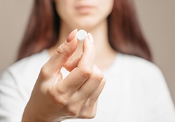 Close up of woman holding a single pill