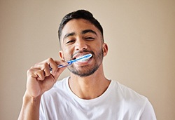 Young man carefully brushing his teeth