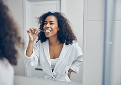 smiling woman brushing her teeth in the bathroom